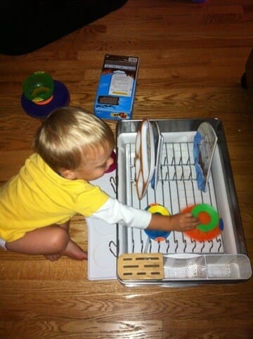 A child putting dishes in a drying rack
