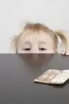 A little girl looking at money on a table