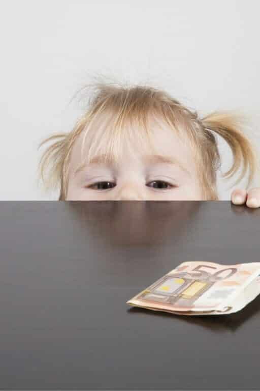 A little girl looking at money on a table