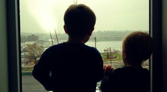 two young boys looking out a window