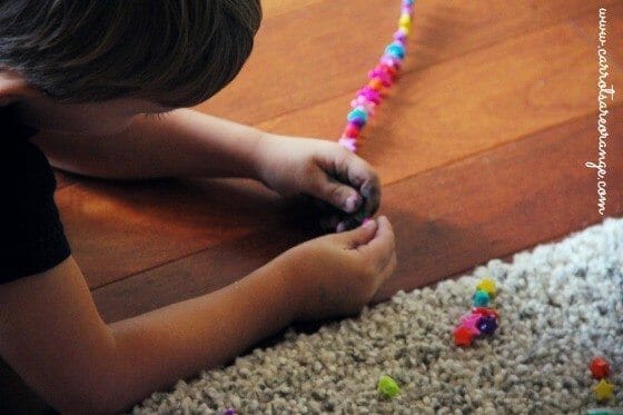 A child  beading with yarn