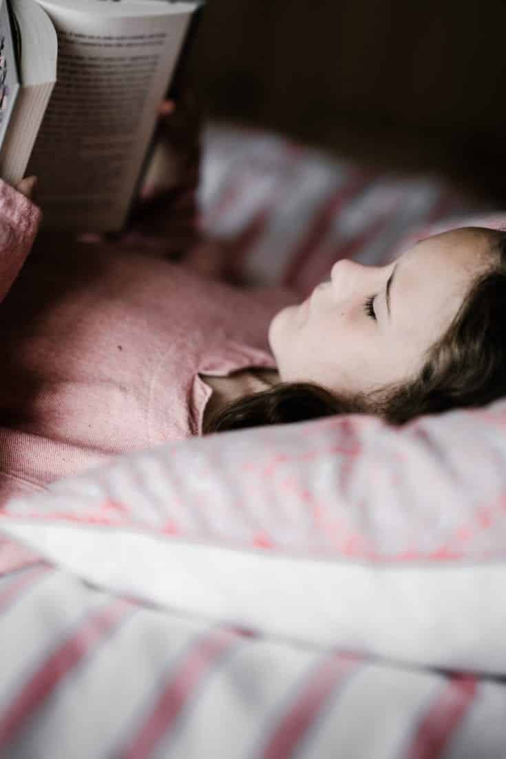 a young girl reading in bed