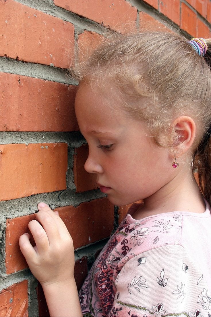 a young girl standing at a wall