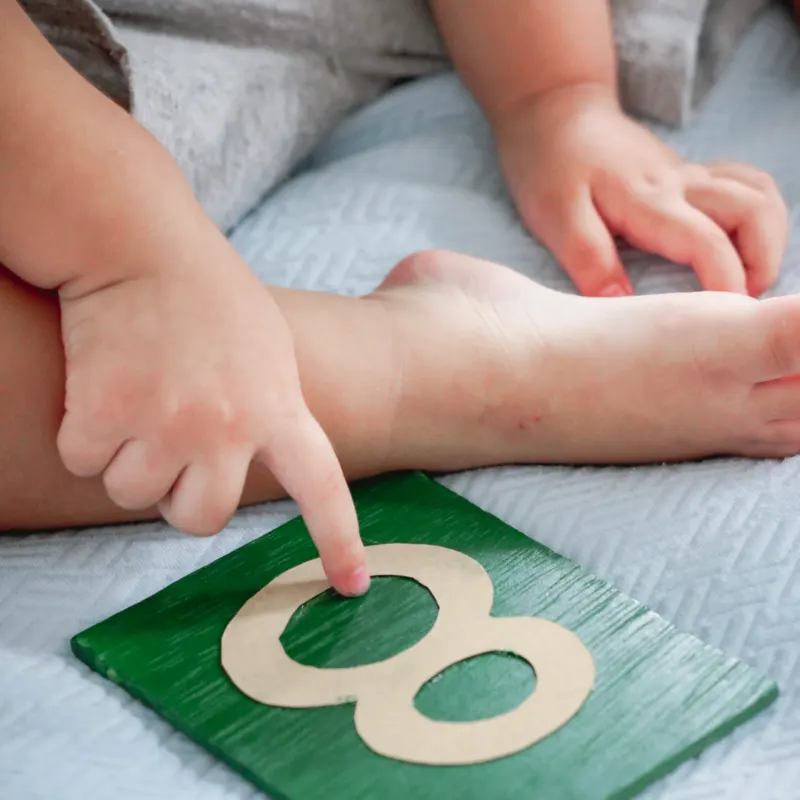 A child tracing a Montessori sandpaper numeral