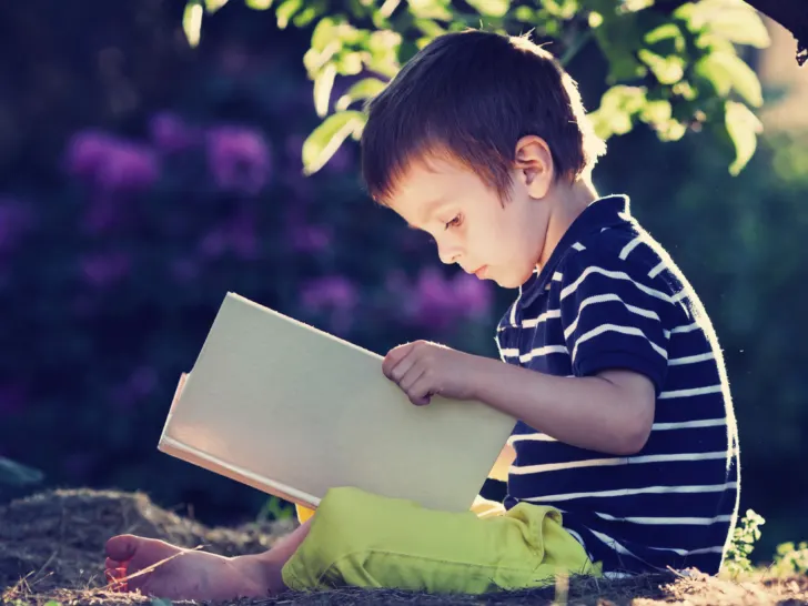 a young boy reading outside