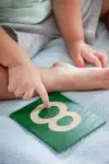 A young boy tracing a sandpaper numeral