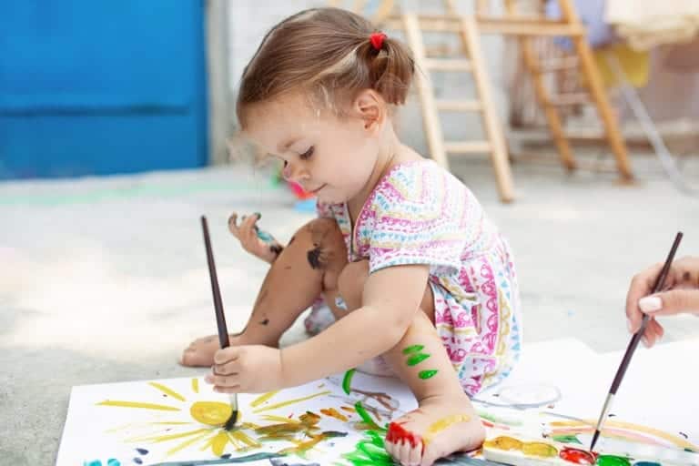 A toddler playing with paint