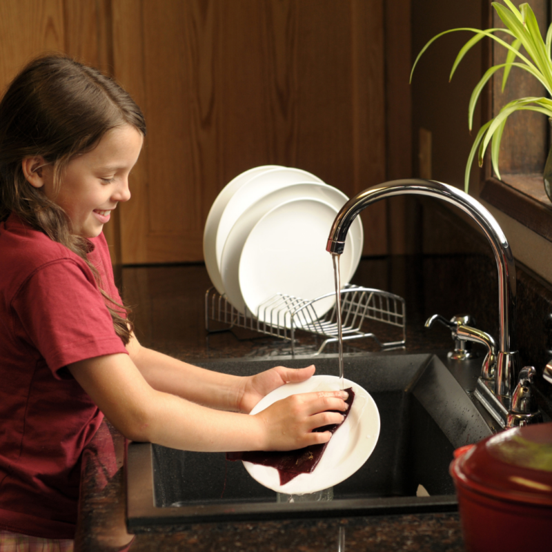 a young girl washing dishes