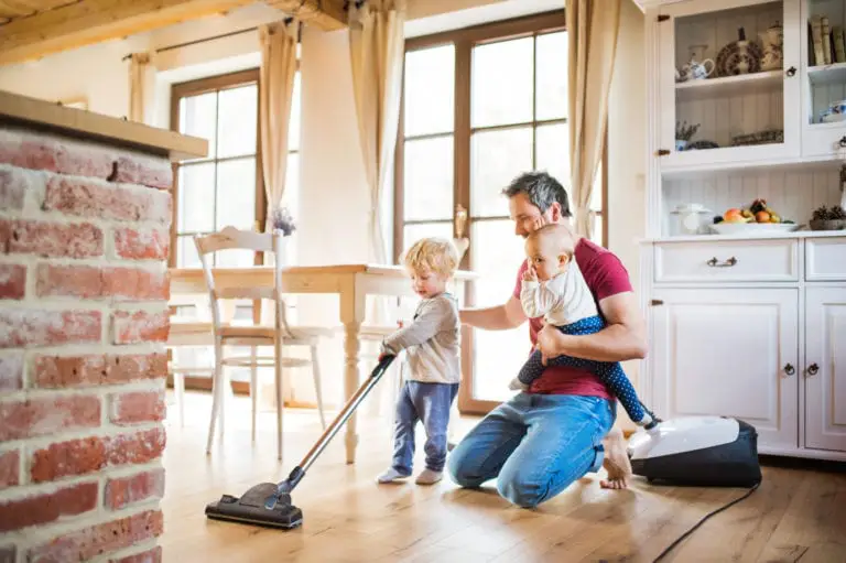 Father and two toddlers doing housework. A child vacuuming.