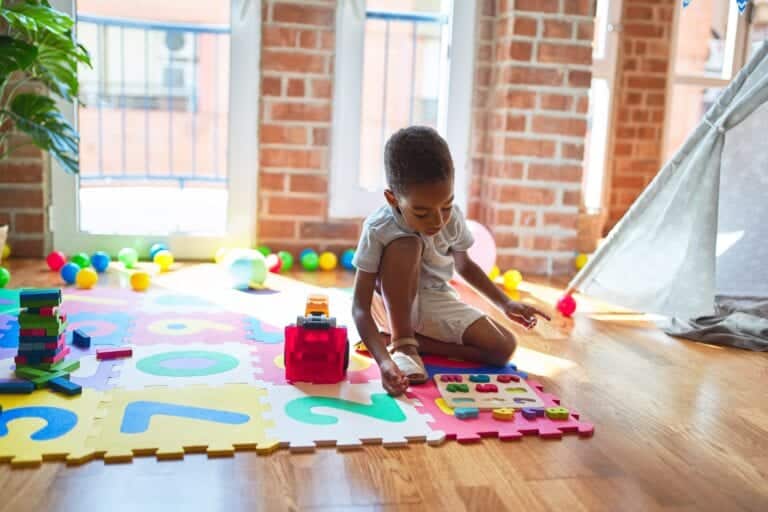 Beautiful african american toddler playing with maths game using numbers at kindergarten