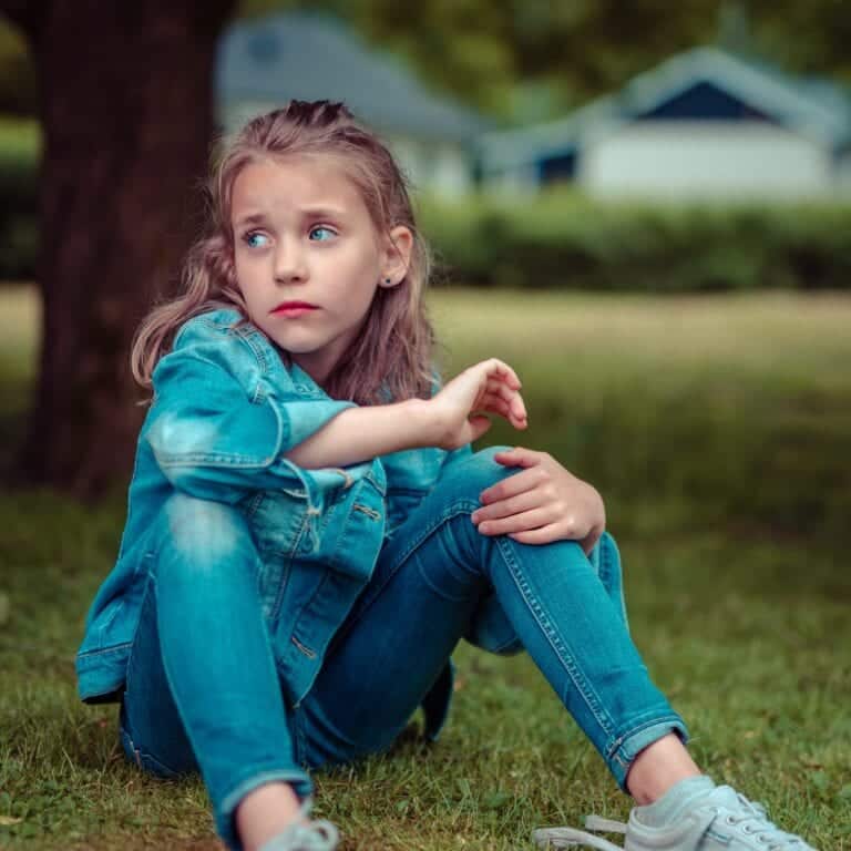 a young girl sitting outside daydreaming