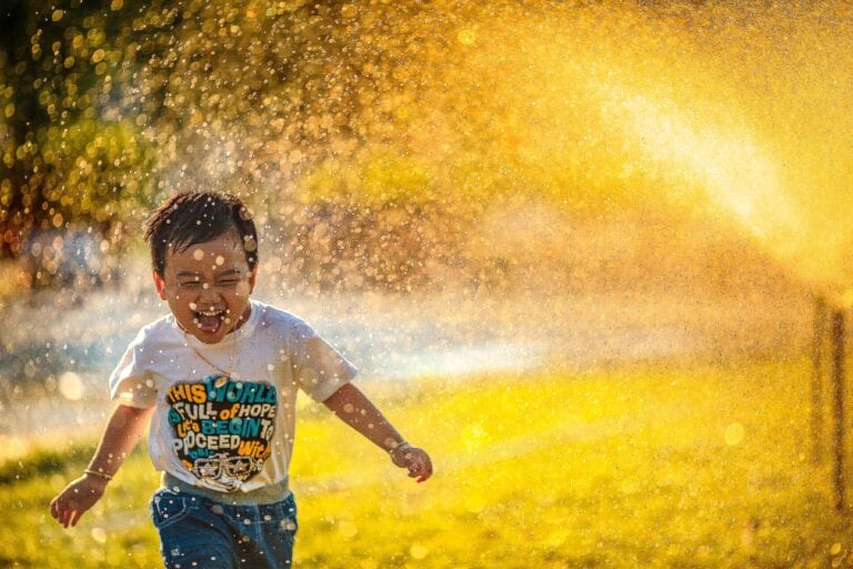 A boy running in the sprinkler