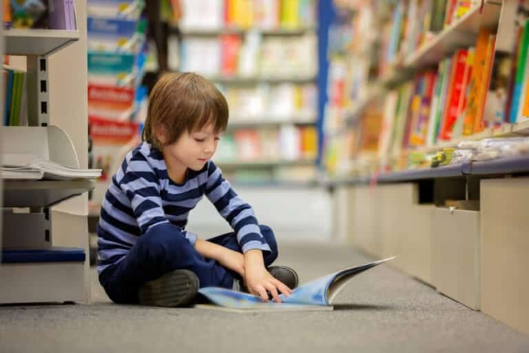 A young child reading on the floor of a library