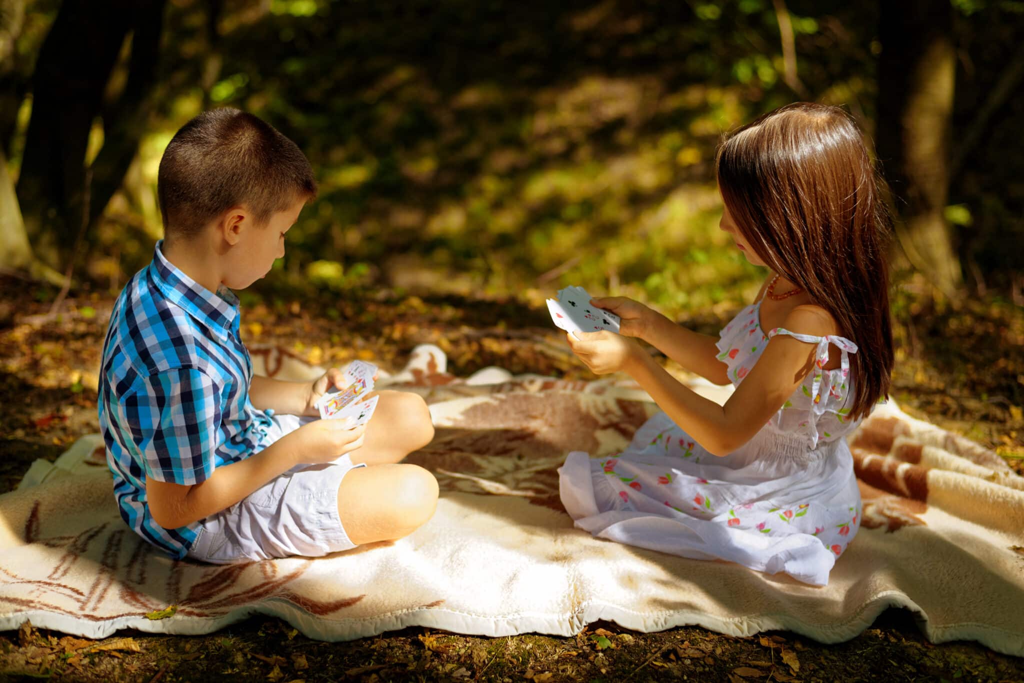 Kids sitting in the forest playing a card game