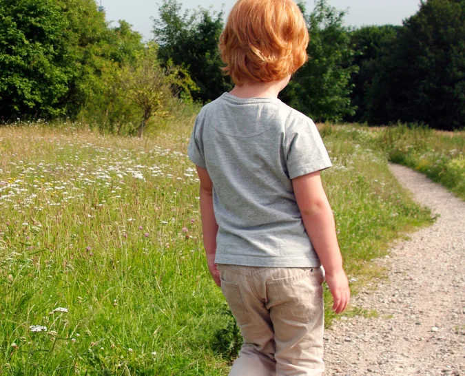 A child walking on a dirt path outside