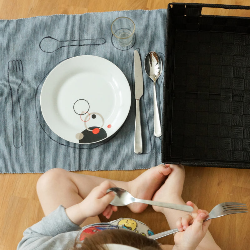 a child sitting at a table with a Montessori placemat