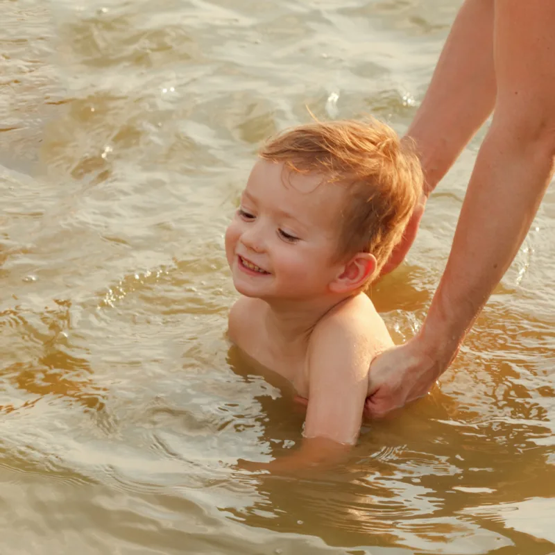 a little boy swimming in a lake