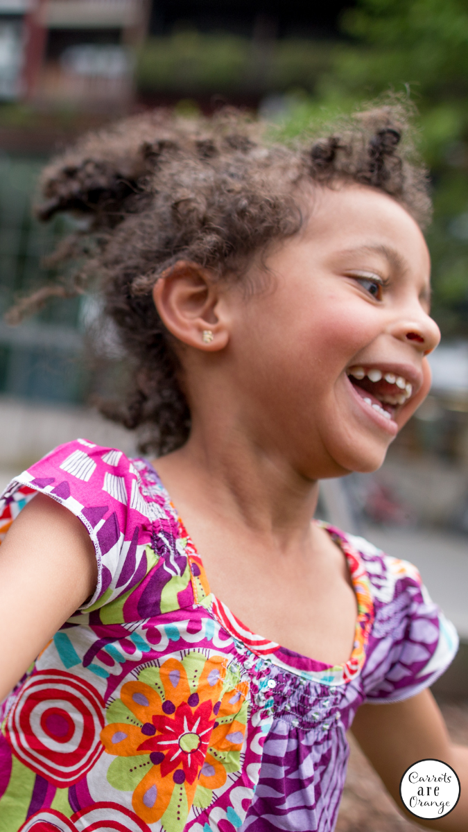 a smiling black girl close up playing outside