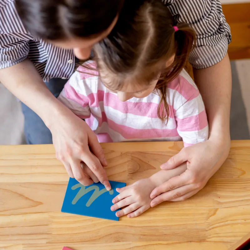 a-child-tracing-a-cursive-montessori-sandpaper-letter