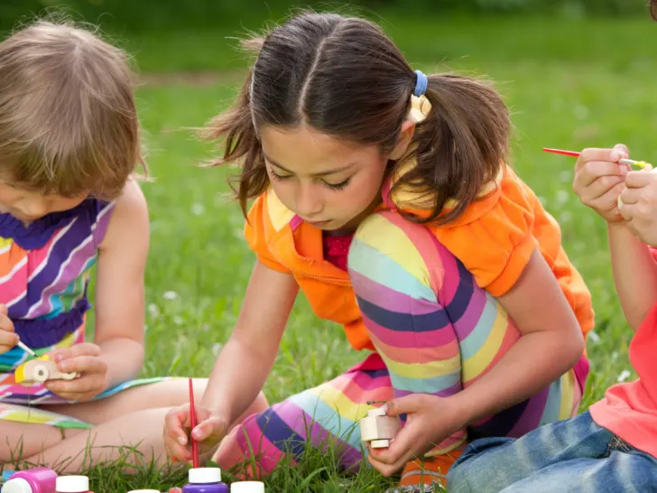 kids painting outdoors in the grass