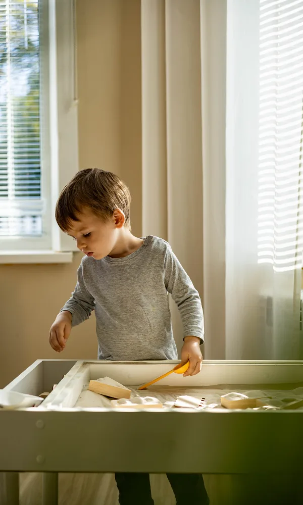 DIY Montessori Sensorial - a young boy playing at a sand table