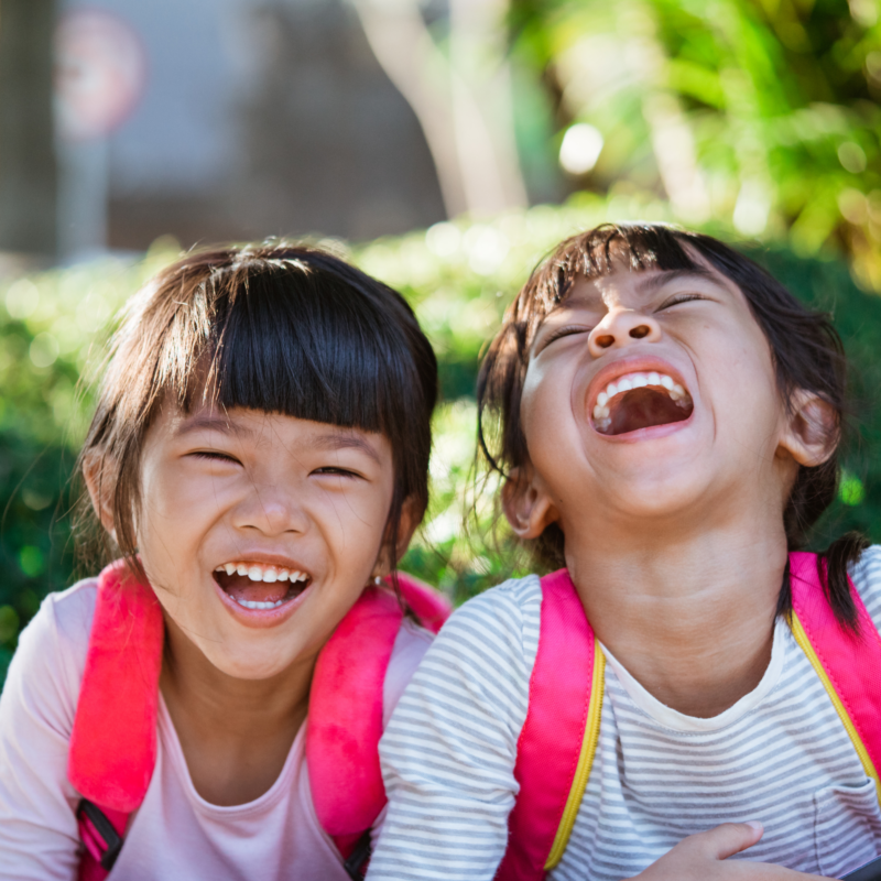 two young asian girls laughing at school