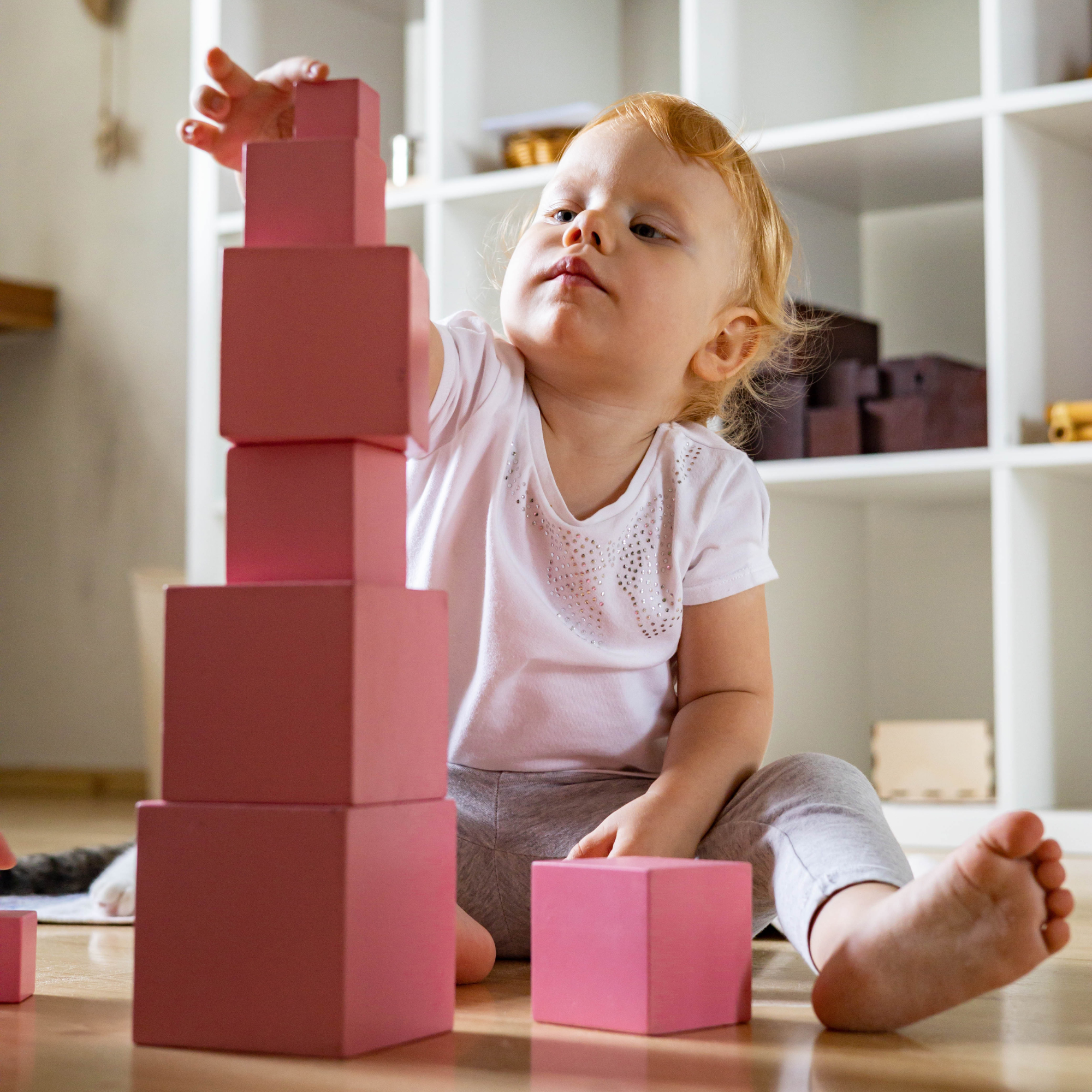 a young child building the pink tower a montessori material in the sensorial area